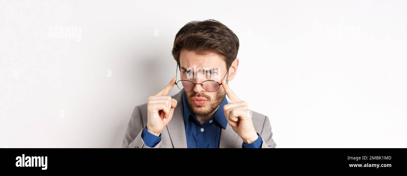 Close-up portrait of suspicious man in suit, taking-off glasses and ...