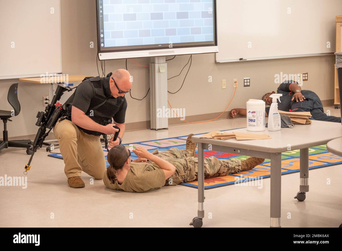 Andrew Stone, a Fort Jackson Department of the Army civilian police officer, applies a tourniquet to the arm of a mock school shooting victim at Pierce Terrance Elementary School June 16, 2022. The active shooter event was part of an annual law enforcement training event where officers entered the classroom alone to neutralize the shooter, treat the wounded with basic first aid, and evacuate the victims to the nearest medical treatment facility. Stock Photo