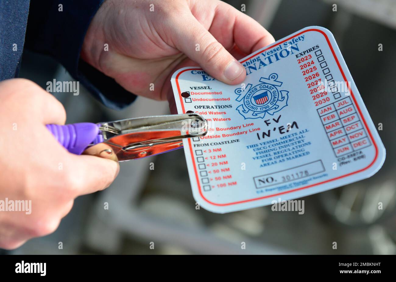 A marine inspector with Coast Guard Sector Anchorage issues a decal to fishing vessel In’Em indicating that it passed a commercial fishing vessel safety exam in Naknek, Alaska, June 16, 2022. Displaying the decal communicates to Coast Guard law enforcement officers on the water that the vessel is in compliance with federal safety laws. U. S. Coast Guard photo by Petty Officer 2nd Class Melissa E. F. McKenzie. Stock Photo