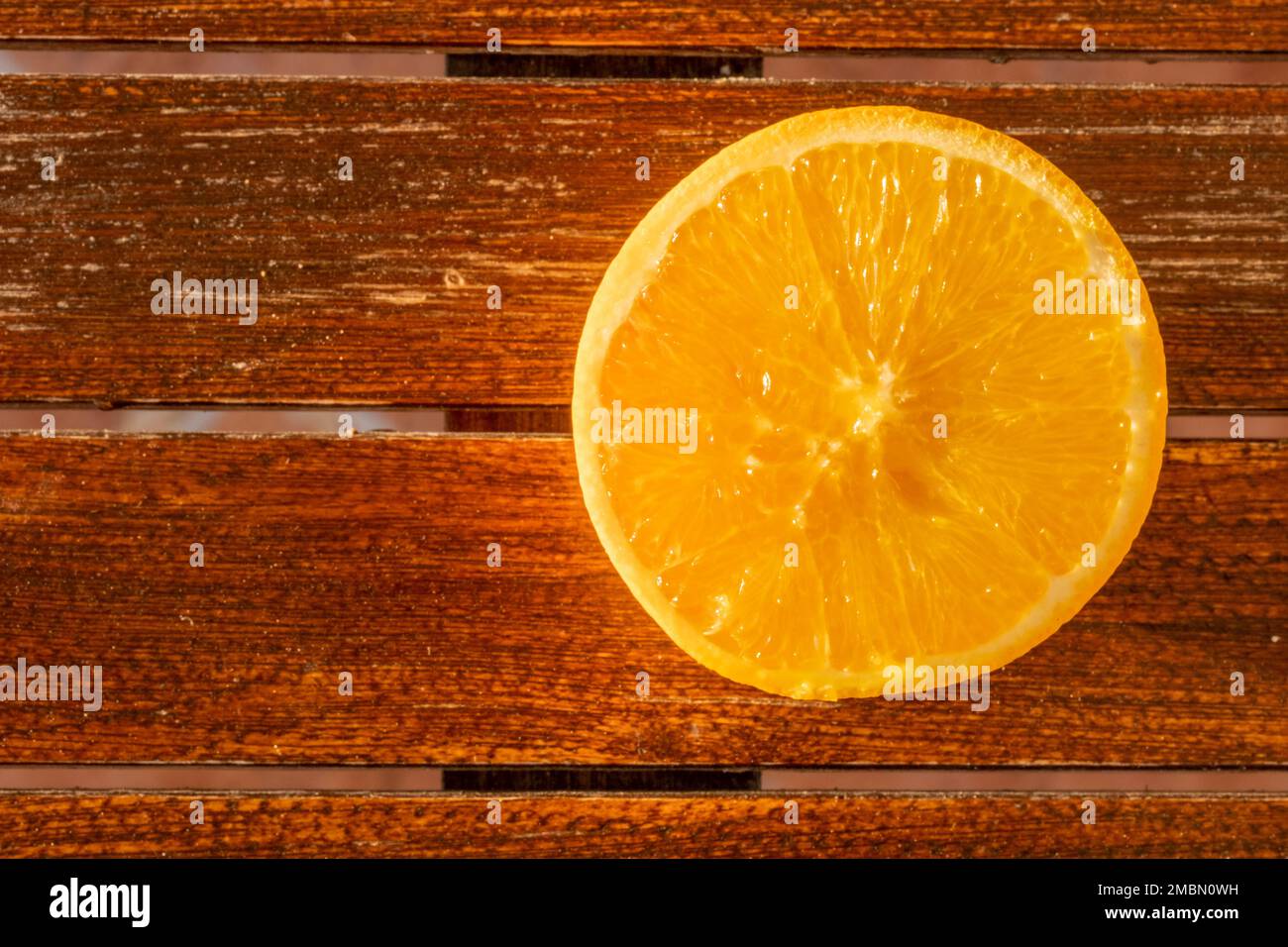 Circle pattern of a freshly cut yellow citrus fruit on wooden table at sun light. Top view on food background with copy space. Stock Photo