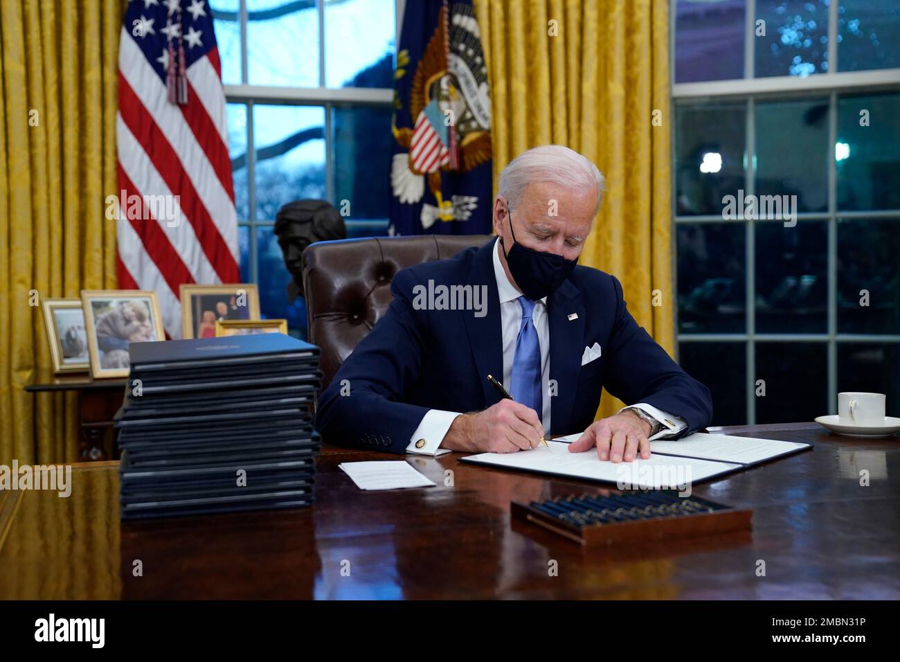 FILE - In this Jan. 20, 2021, file photo, President Joe Biden signs his first executive order in the Oval Office of the White House in Washington.Biden laid out an ambitious agenda for his first 100 days in office, promising swift action on everything from climate change to immigration reform to the coronavirus pandemic. Key members of the White House Environmental Justice Advisory Council say one year into the Biden Administration's commitment that 40% of all benefits from climate investment go to disenfranchised communities, not enough has been done. (AP Photo/Evan Vucci, File) Stock Photo