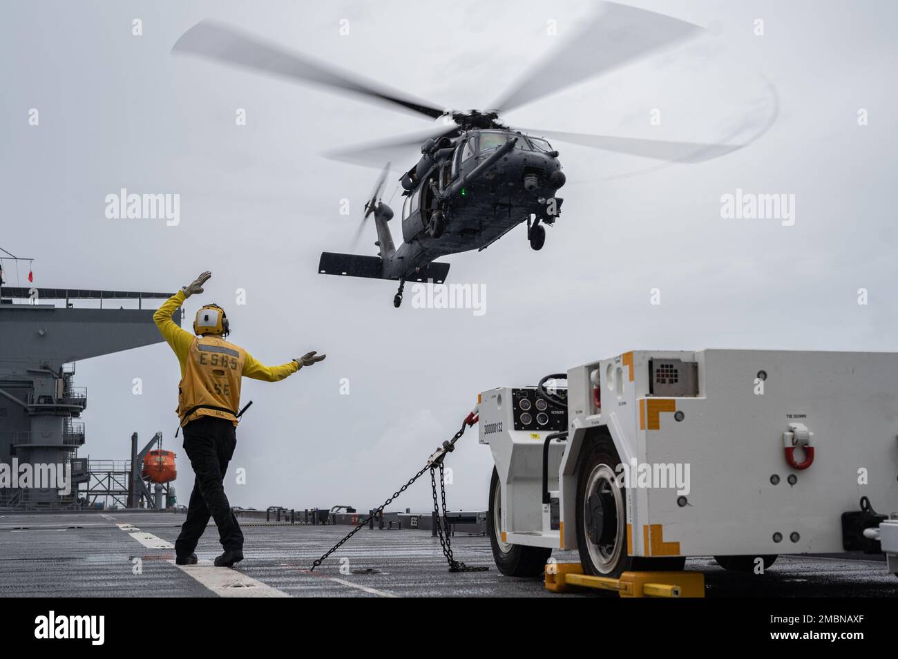 A U.S. Navy aircraft director guides a 33rd Rescue Squadron HH-60G Pave ...