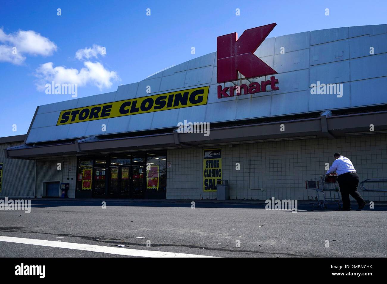 A man pushes a cart through the parking lot of a Kmart in Avenel, N.J