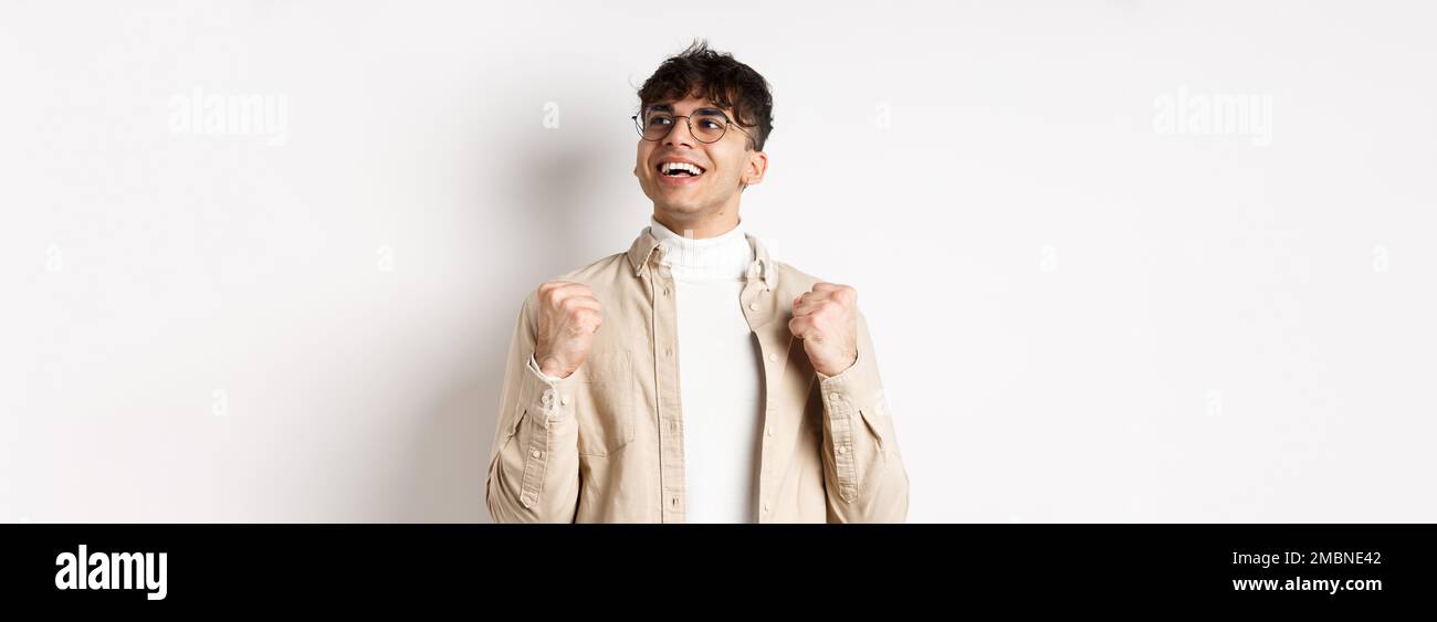 Lucky young man say yes with relieved face, smiling and making fist ...