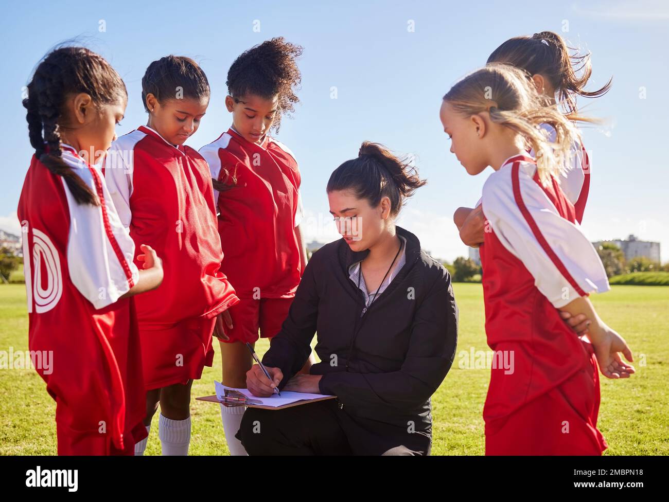 Planning, sports and coach with children for soccer strategy, training and team goals in England. Plan, teamwork and woman coaching a group of girls Stock Photo