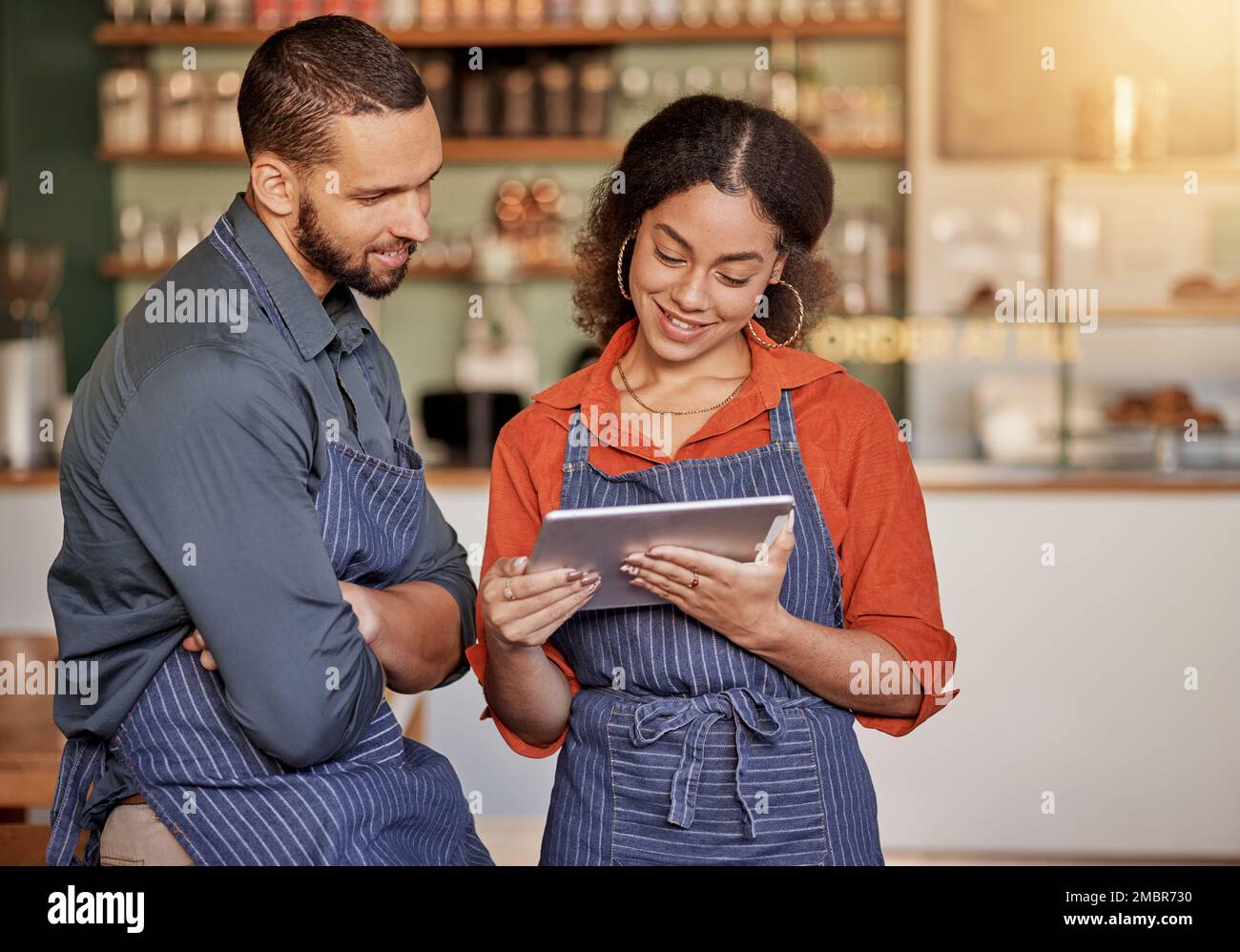 Restaurant, cafe teamwork and couple with tablet to manage orders, inventory and stock check. Diversity, waiter technology and man and woman with Stock Photo