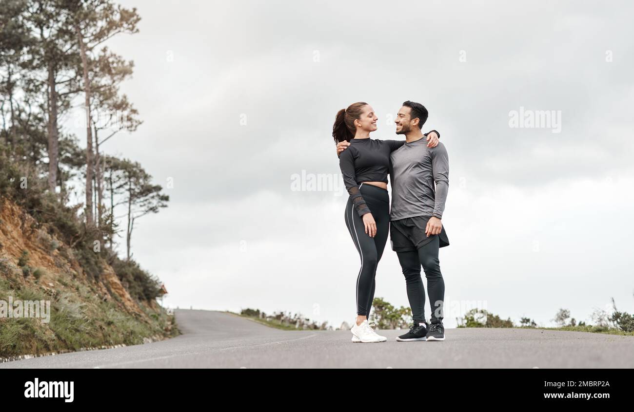 One good gym buddy is all you need. Full length shot of two young athletes standing with their arms around each other after their morning run outdoors Stock Photo