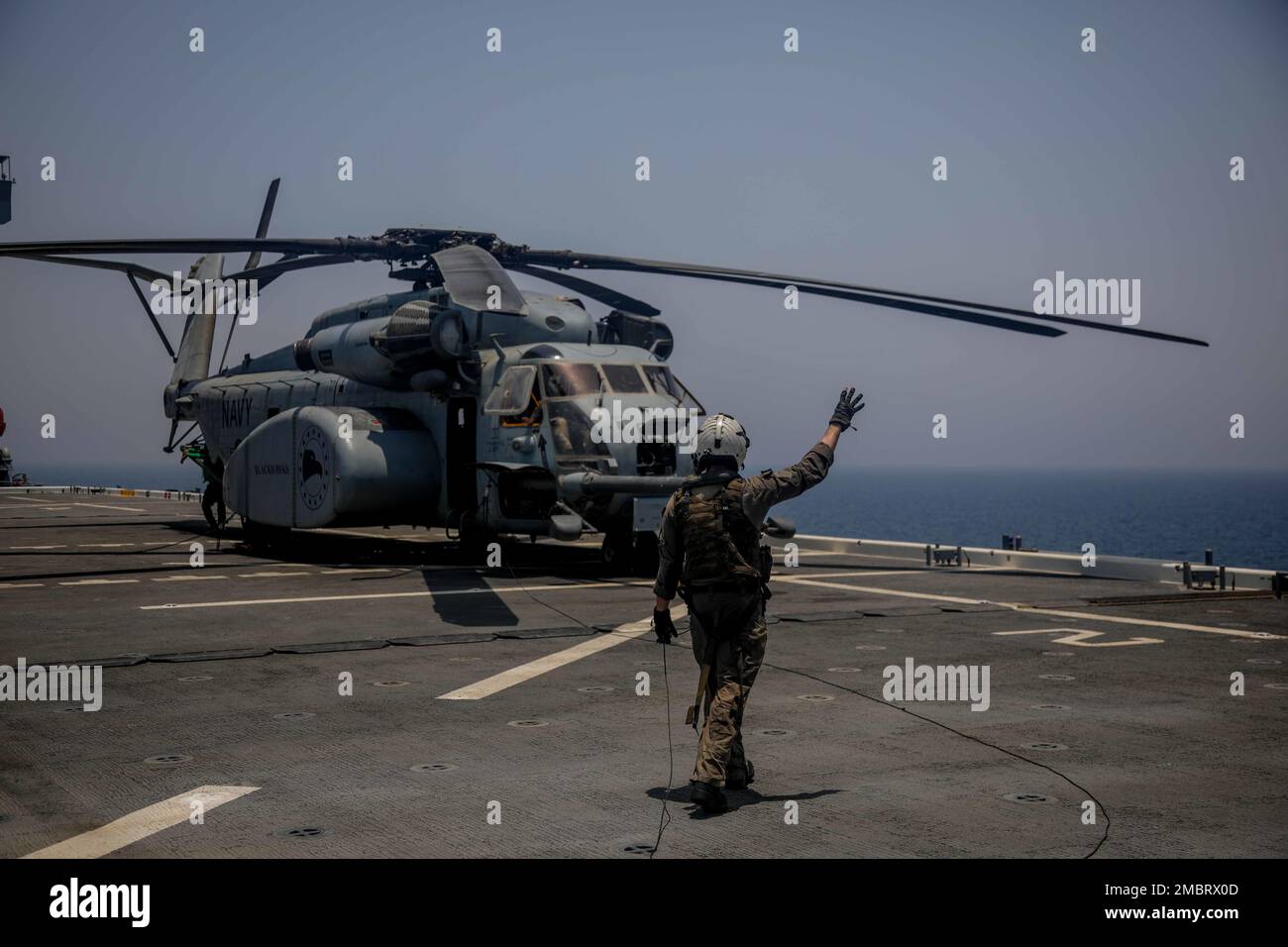 220621-A-EQ028-1055 ARABIAN GULF (June 21, 2022) Aviation Warfare Systems 3rd Class Kyle Gumz directs an MH-53 Sea Dragon helicopter, attached to Helicopter Mine Countermeasures (HM) Squadron 15, during flight operations aboard the expeditionary sea base USS Lewis B. Puller (ESB 3), during exercise Iron Defender in the Arabian Gulf, June 21. Iron Defender is an annual bilateral training event between U.S. Naval Forces Central Command and forces from the United Arab Emirates. The exercise focuses on maritime security operations, mine countermeasures, and harbor defense. Stock Photo