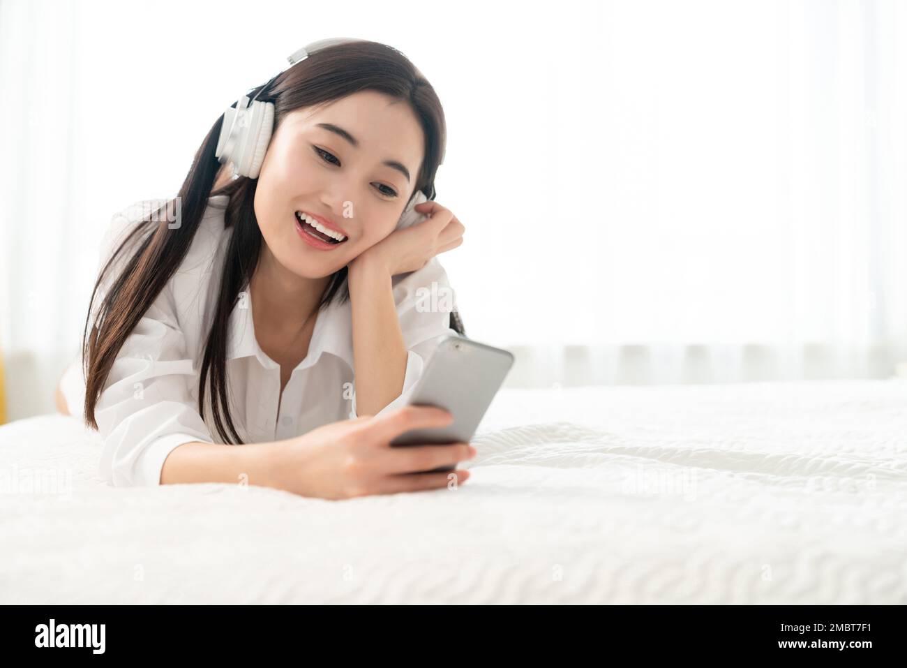 A young woman lying on the bed to listen to music Stock Photo - Alamy