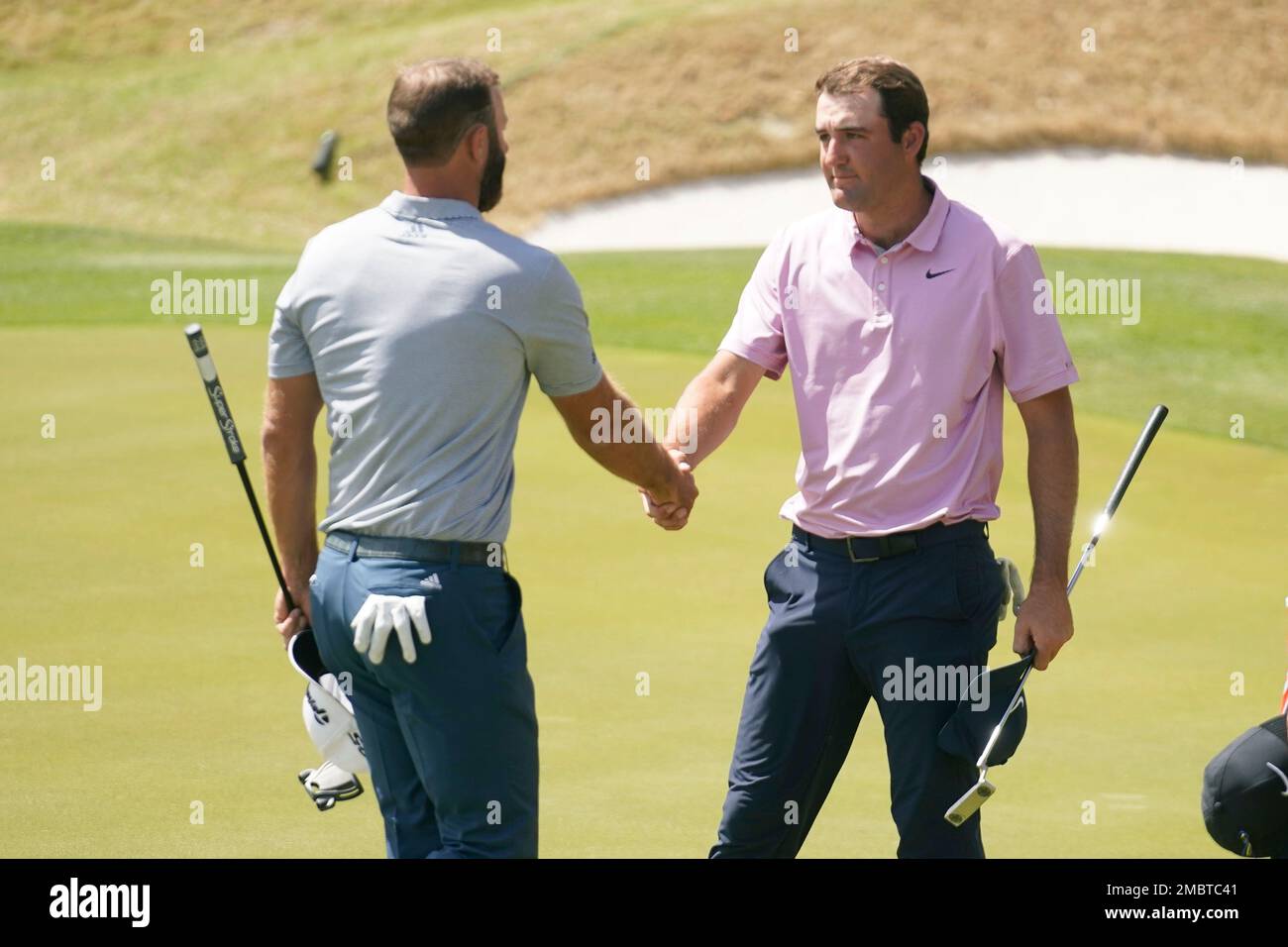 Scottie Scheffler, right, shakes hands after defeating Dustin Johnson