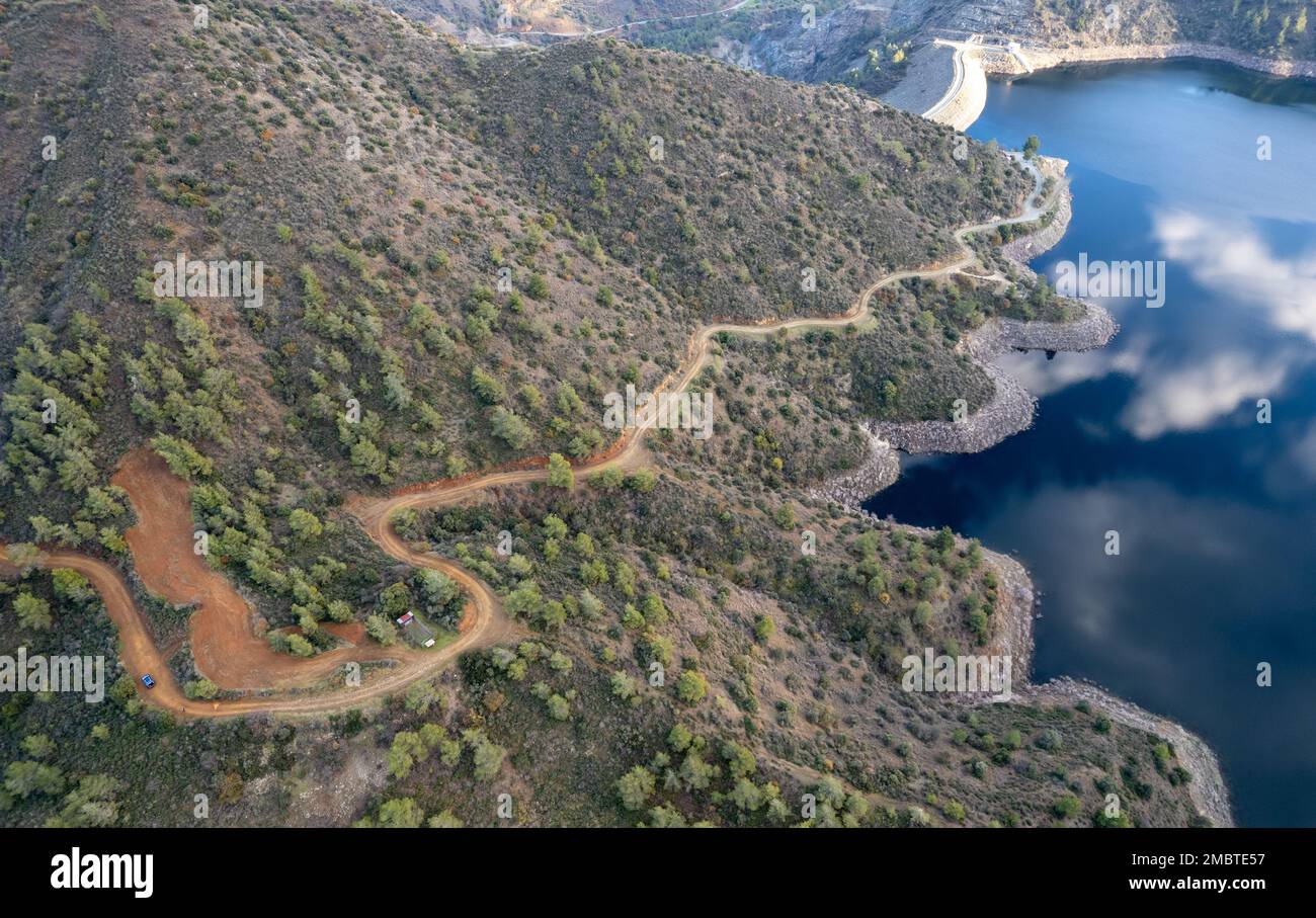 Drone aerial of rural curved road passing through the mountain. and reservoir dam. Discovery and adventure in nature. Troodos Cyprus Stock Photo