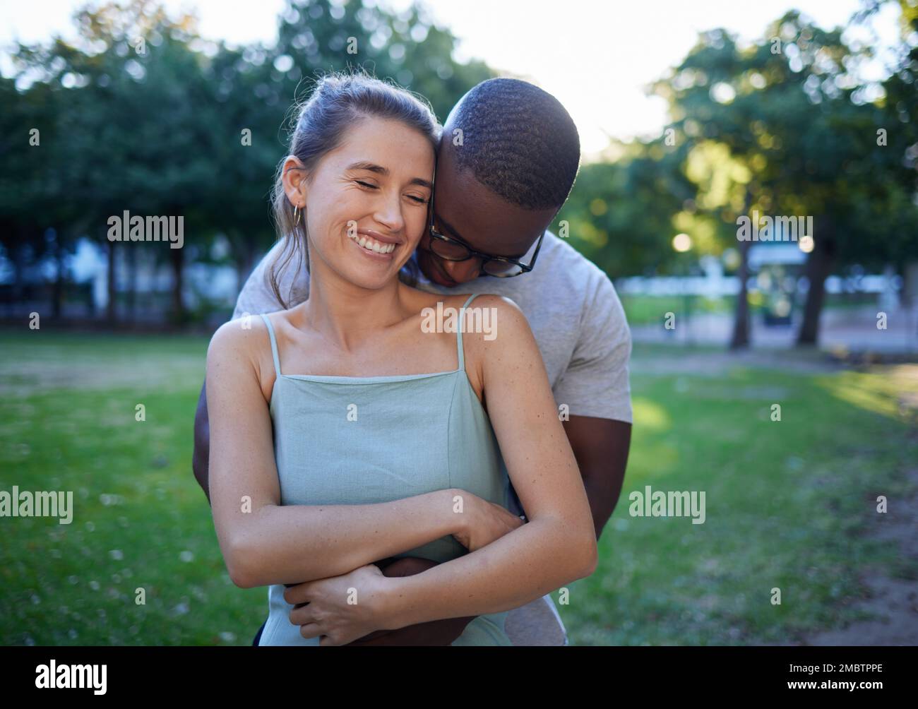 Happy interracial couple, hug and smile for romance, love or care or ...