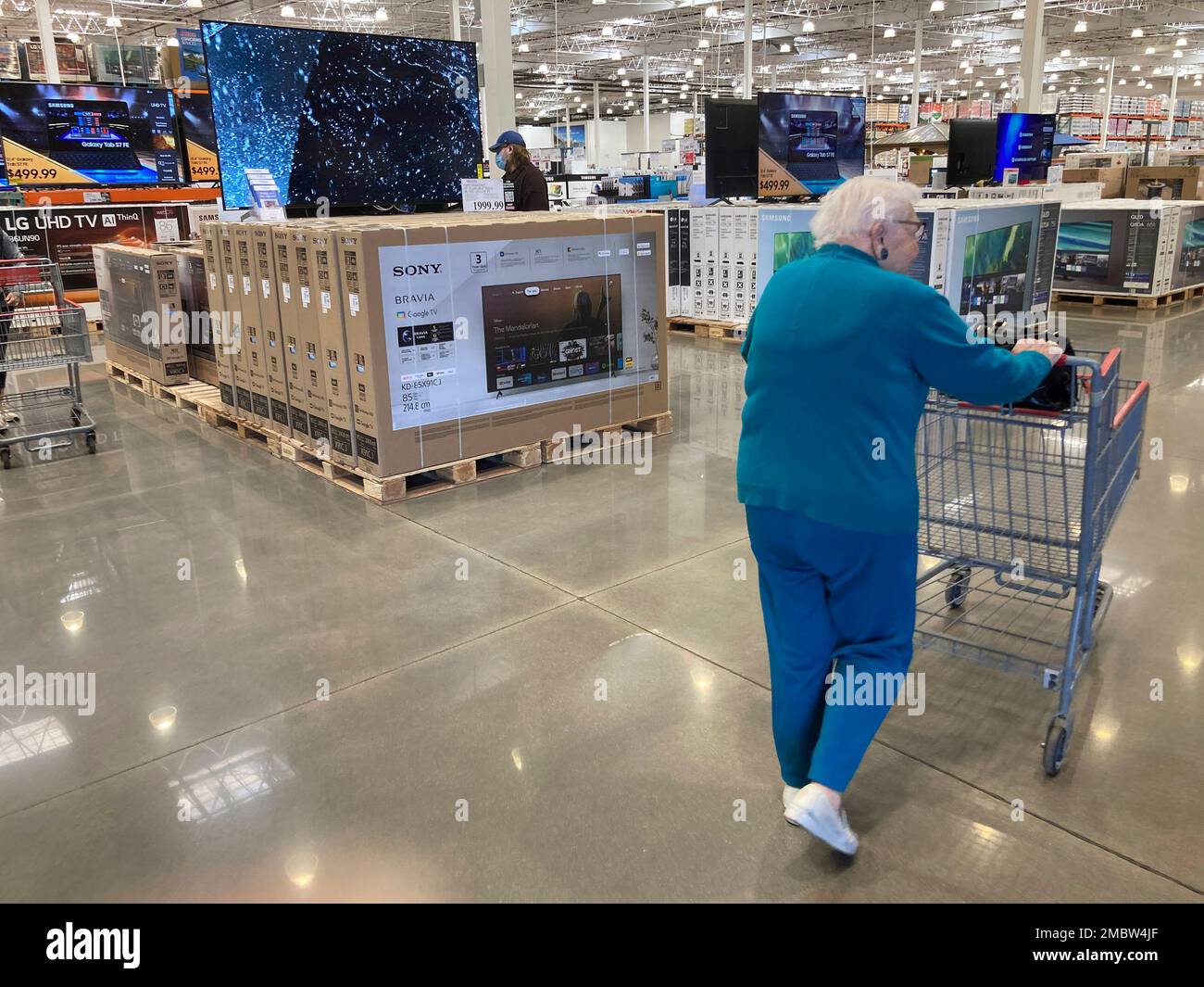 A shopper guides a cart past a display of big-screen television sets in ...