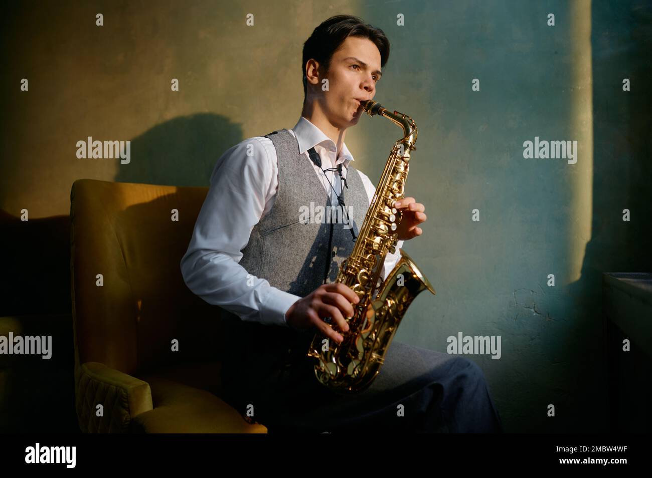 Jazz musician playing saxophone in front of window Stock Photo