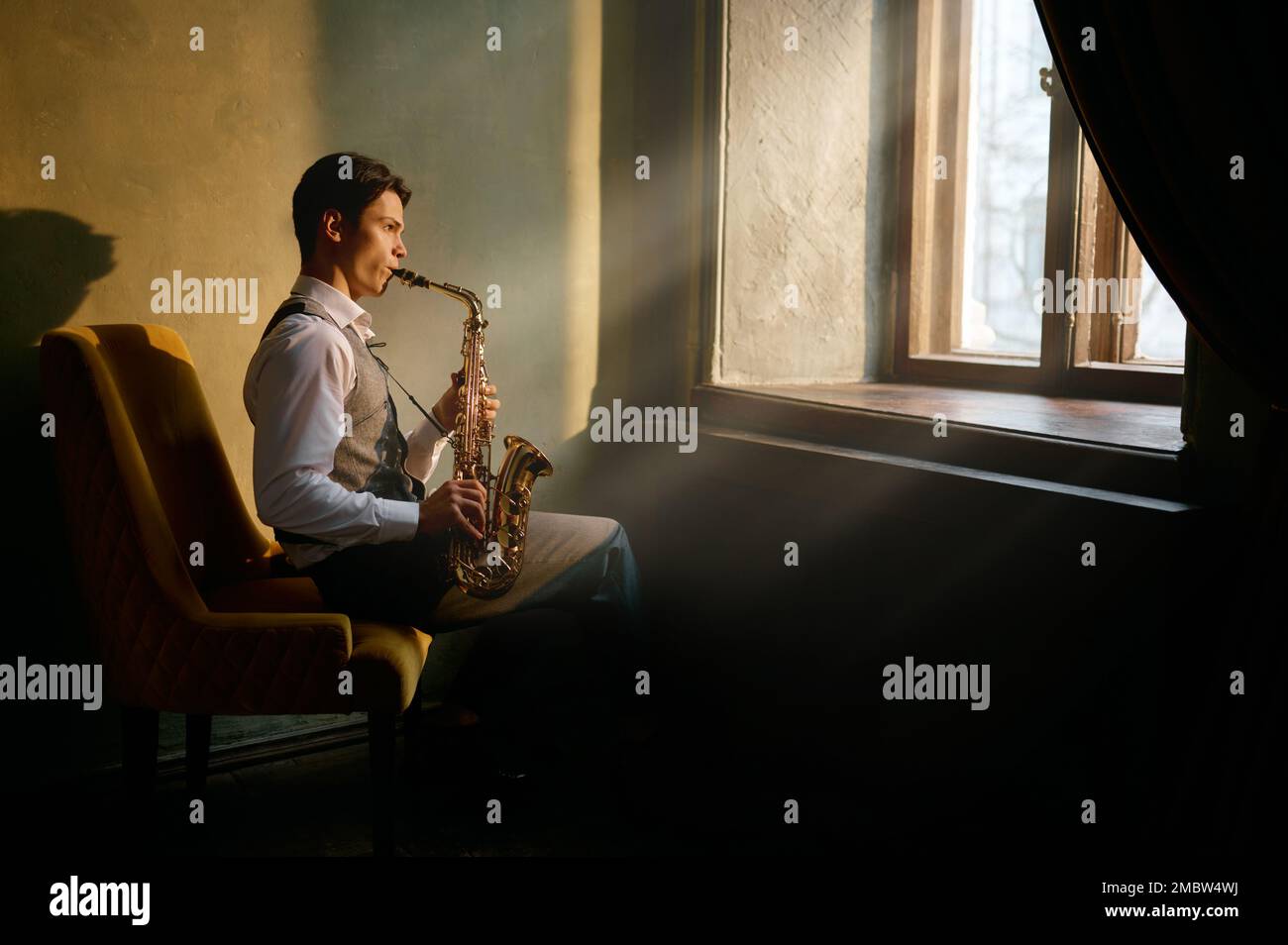Jazz musician playing saxophone at the window Stock Photo