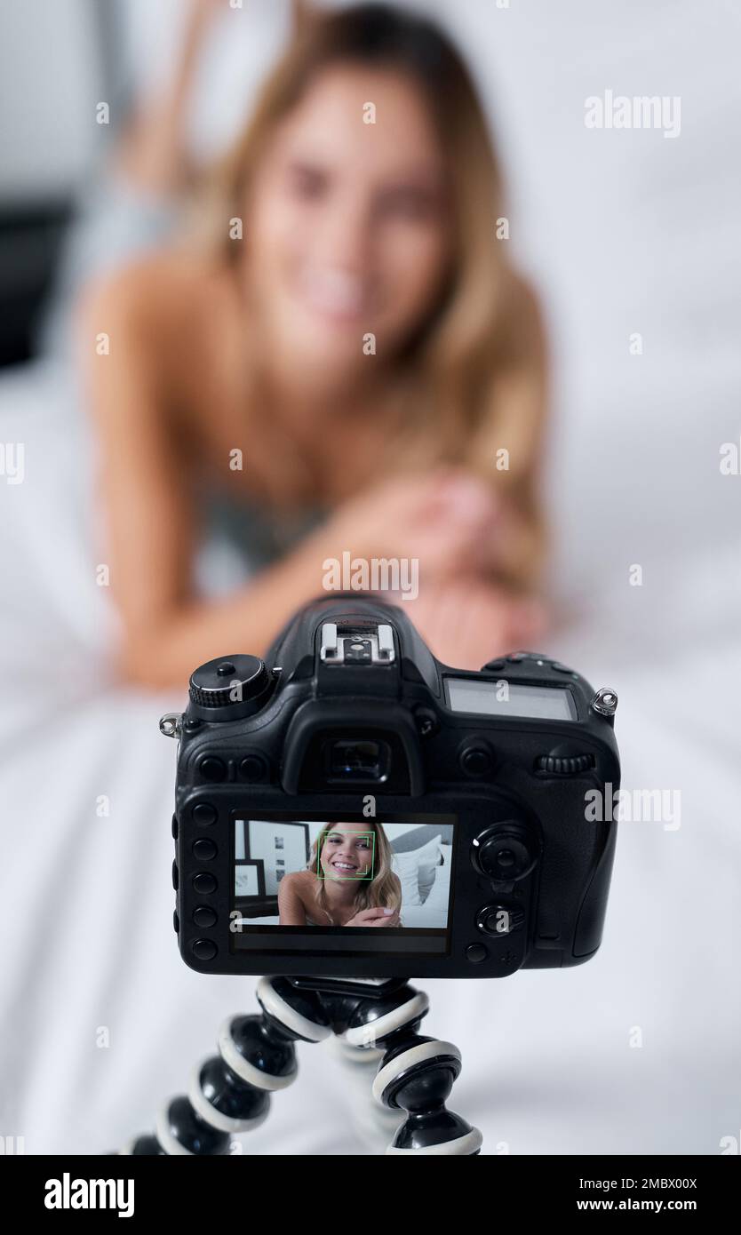 I have so much to tell you guys. a young woman using a tripod while recording herself at home. Stock Photo