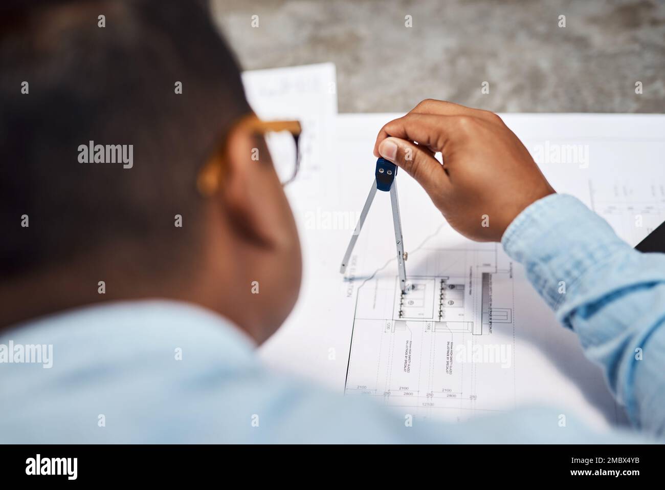 Its no wonder his designs are on point. an architect using a compass to draw a building plan. Stock Photo