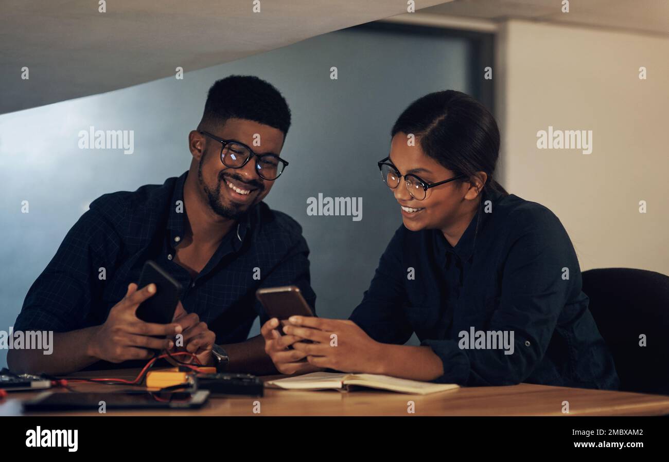 Computer repair service you can count on. two young technicians using their smartphone while repairing computer hardware. Stock Photo