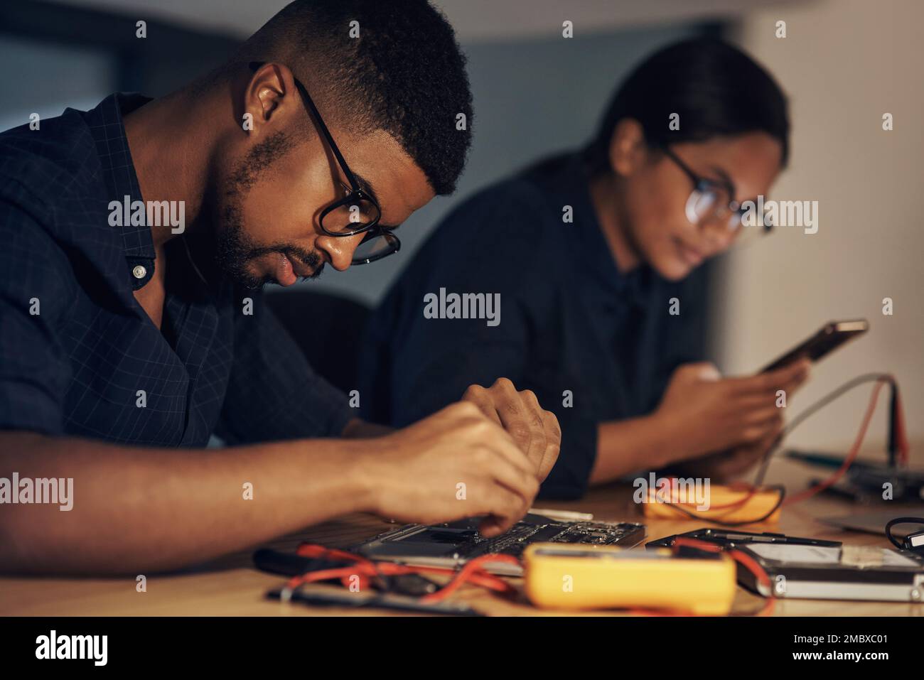 The hardest working tech repair team. two young technicians repairing computer hardware together. Stock Photo