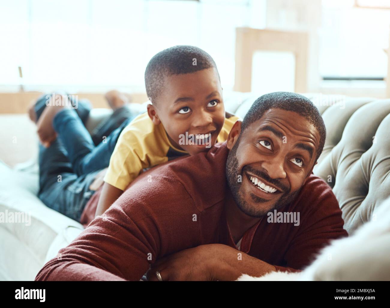 Happy family, father and son on sofa, relax and play, happy and smile while bond in their home. Love, parent and child excited, playful and cheerful Stock Photo