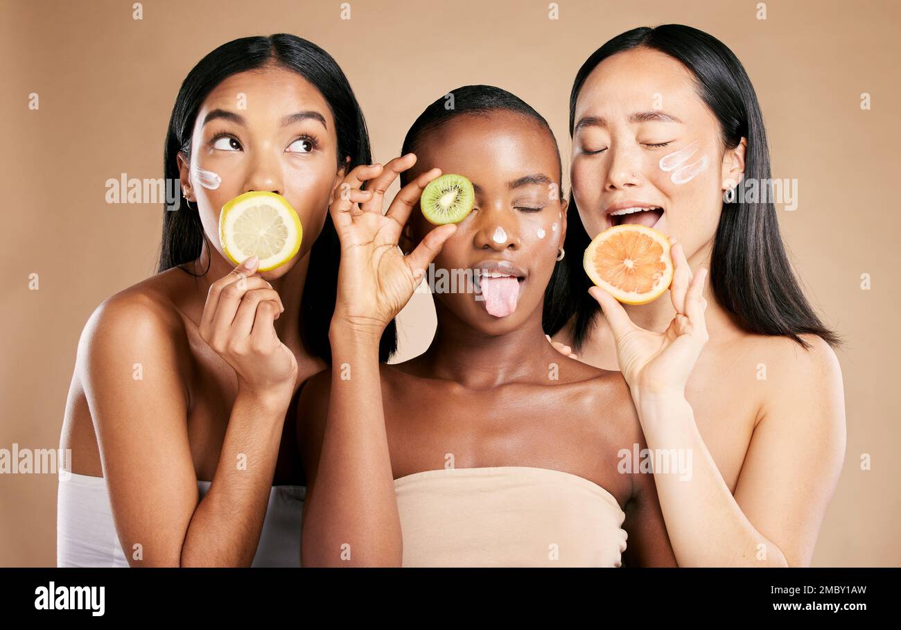 Diversity, women and fruit for natural beauty, dermatology and healthy lifestyle with girls on brown studio background. Cosmetics, friends or ladies Stock Photo