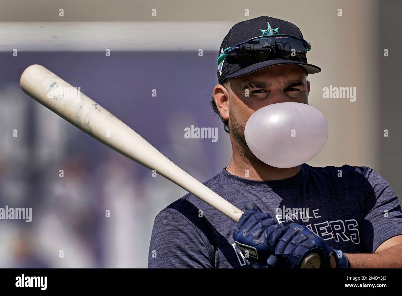 Seattle Mariners' Eugenio Suarez blows a bubble as he waits to bat