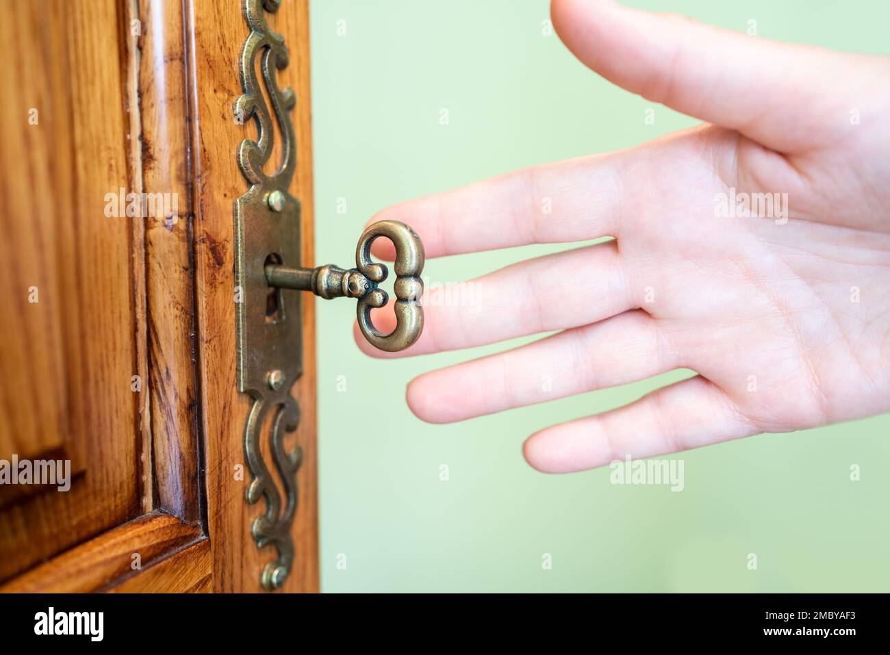 Women hand puts the key in the keyhole of a clothes closet Stock Photo