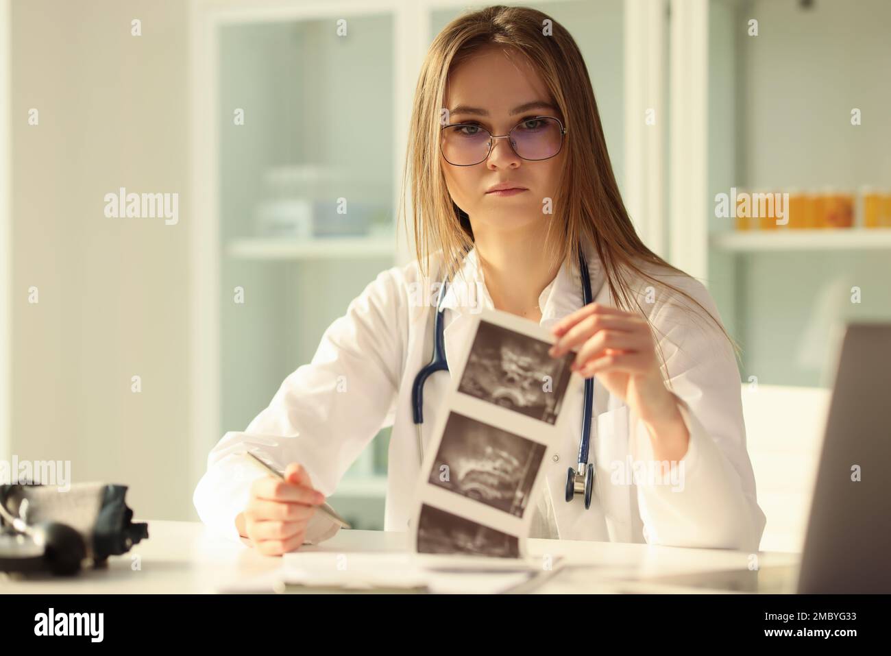 Doctor therapist examining result of ultrasound examination of abdominal cavity in clinic Stock Photo