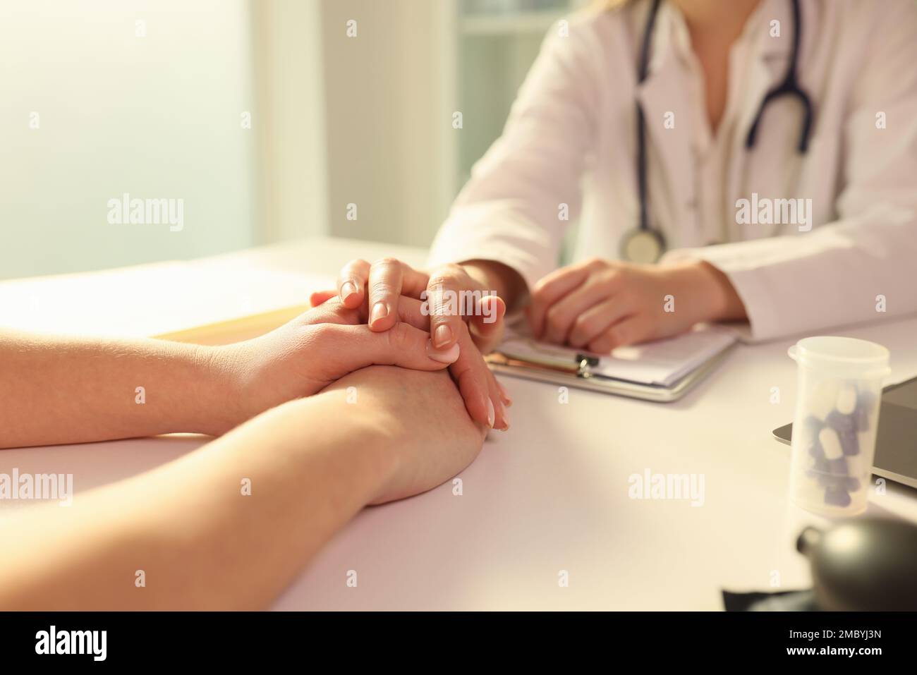 Doctor with his hand calming patient in clinic closeup Stock Photo