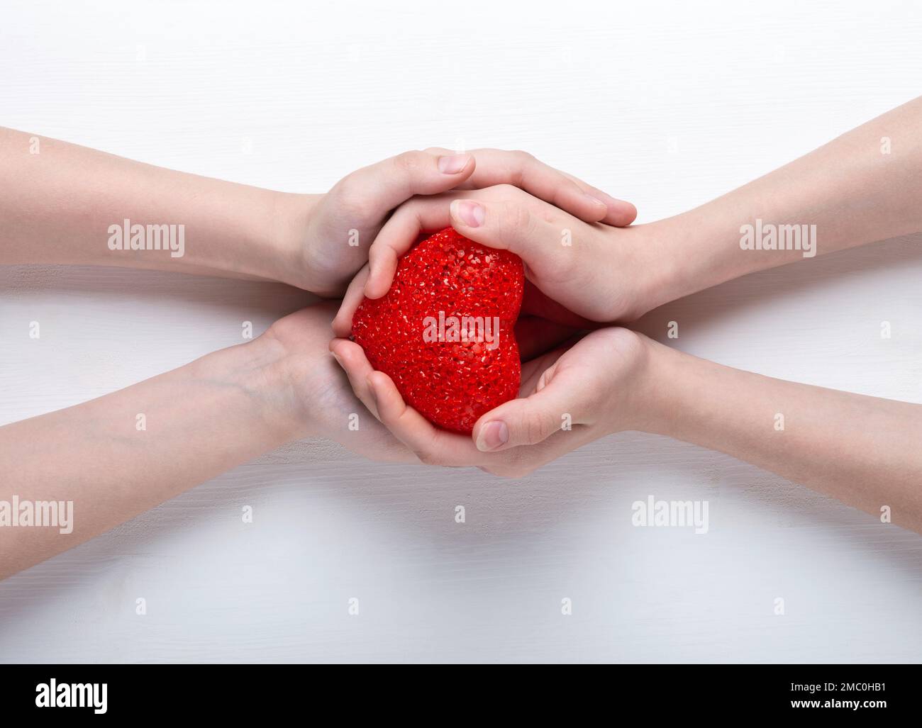Red heart in the hands of a boy and a girl, on a white background Stock ...