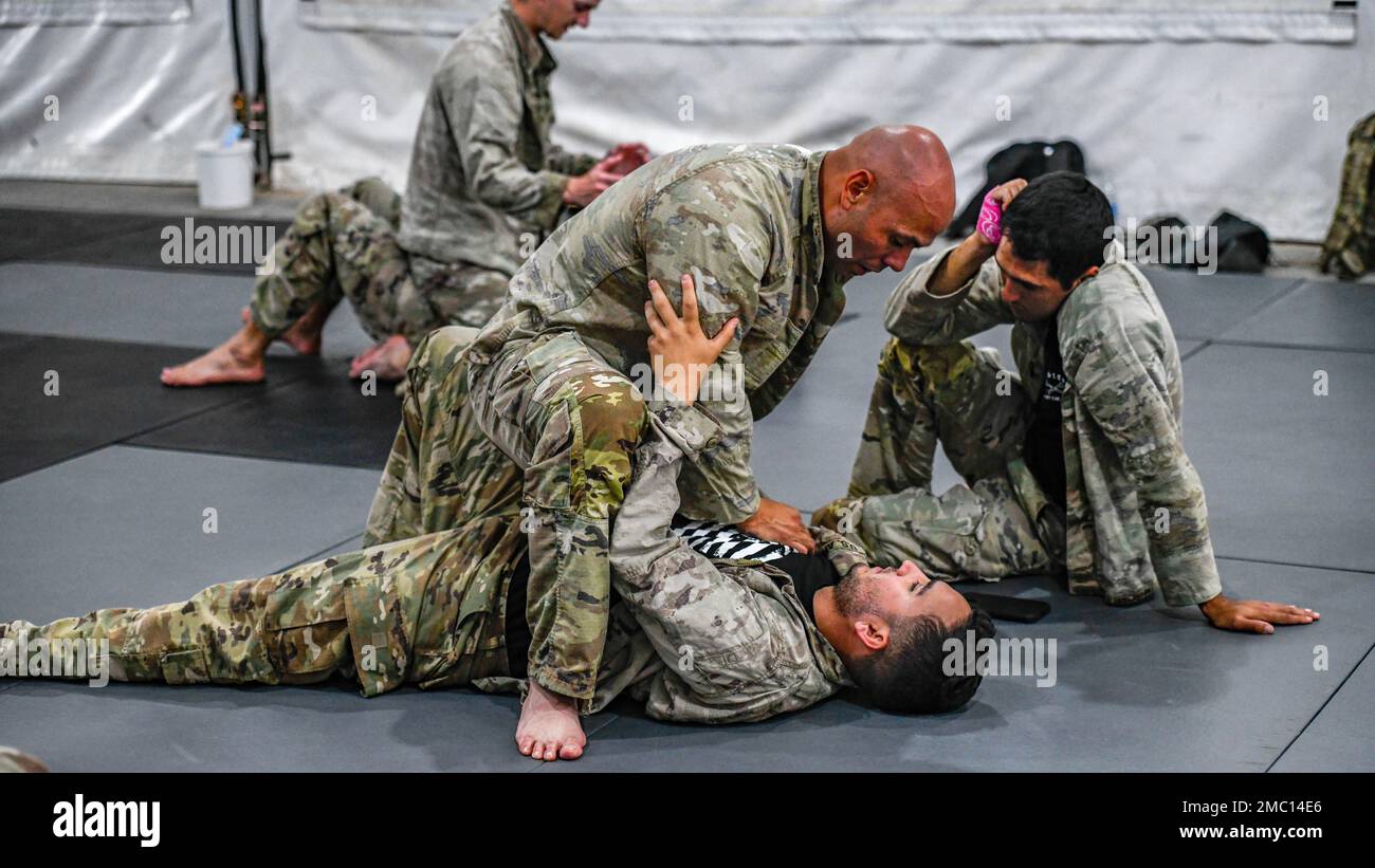 A U.S. Soldier, assigned to Task Force Hurricane, explains the next step in putting his opponent into a takedown position during a one-week combative level 1 qualification course at Prince Sultan Air Base, Kingdom of Saudi Arabia, June 23, 2022. The 40 hr. course allows graduates to teach others the 14 basic combative moves and two takedowns covered in level 1, only level 2 combative graduates or higher can qualify students. Two U.S. Air Force Defenders assigned to the 378th Expeditionary Security Forces Squadron participated in the course. Stock Photo