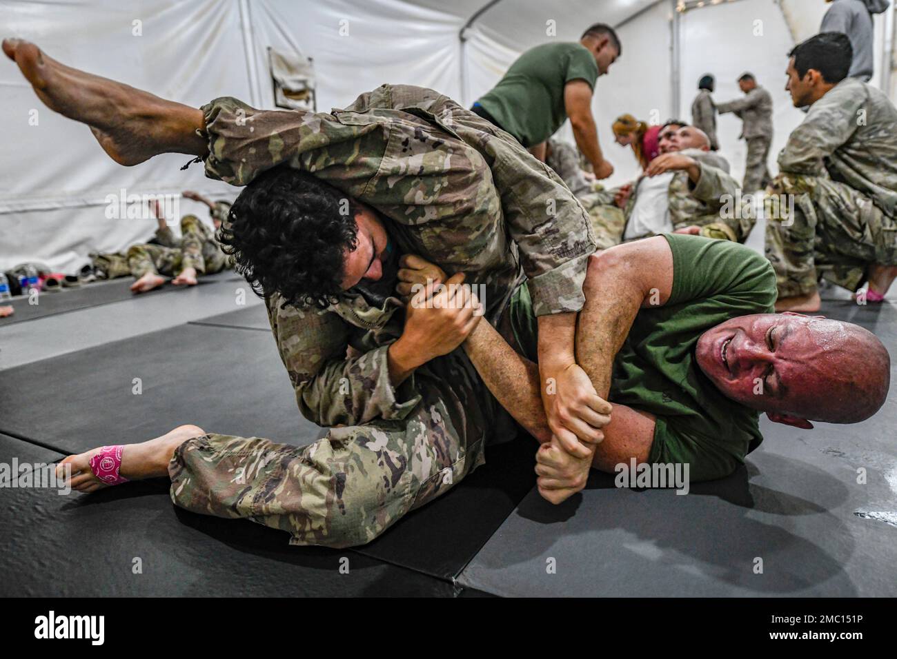 Two U.S. Soldiers, assigned to Task Force Hurricane, fight to take each other down as a one-week combative level 1 qualification course at Prince Sultan Air Base, Kingdom of Saudi Arabia, is instructed in the background, June 23, 2022. The 40 hr. course allows graduates to teach others the 14 basic combative moves and two takedowns covered in level 1, only level 2 combative graduates or higher can qualify students. Two U.S. Air Force Defenders assigned to the 378th Expeditionary Security Forces Squadron participated in the course. Stock Photo