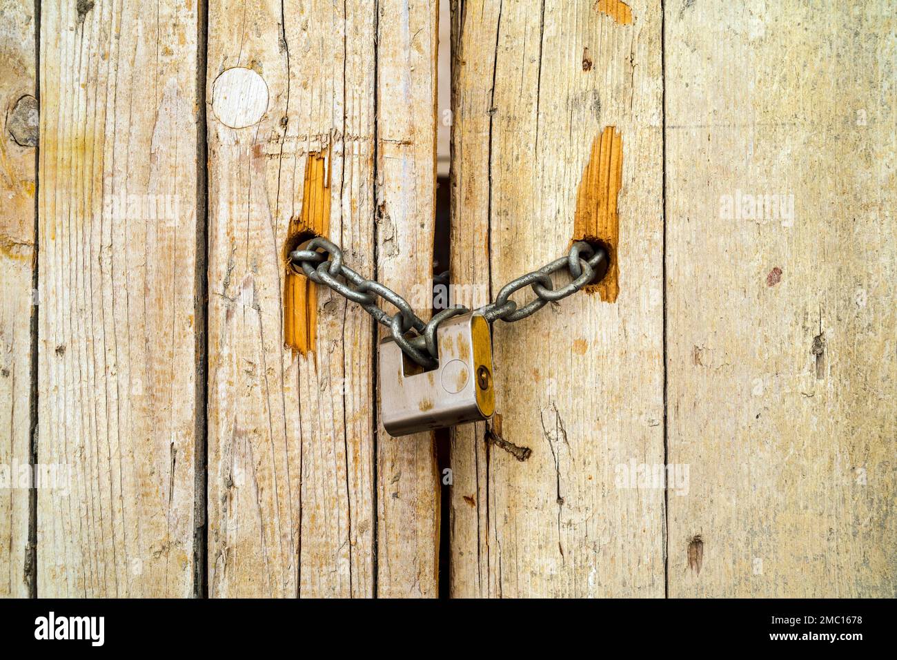 Rusty padlock locking old wooden door with a chain, Tavira, Portugal Stock Photo