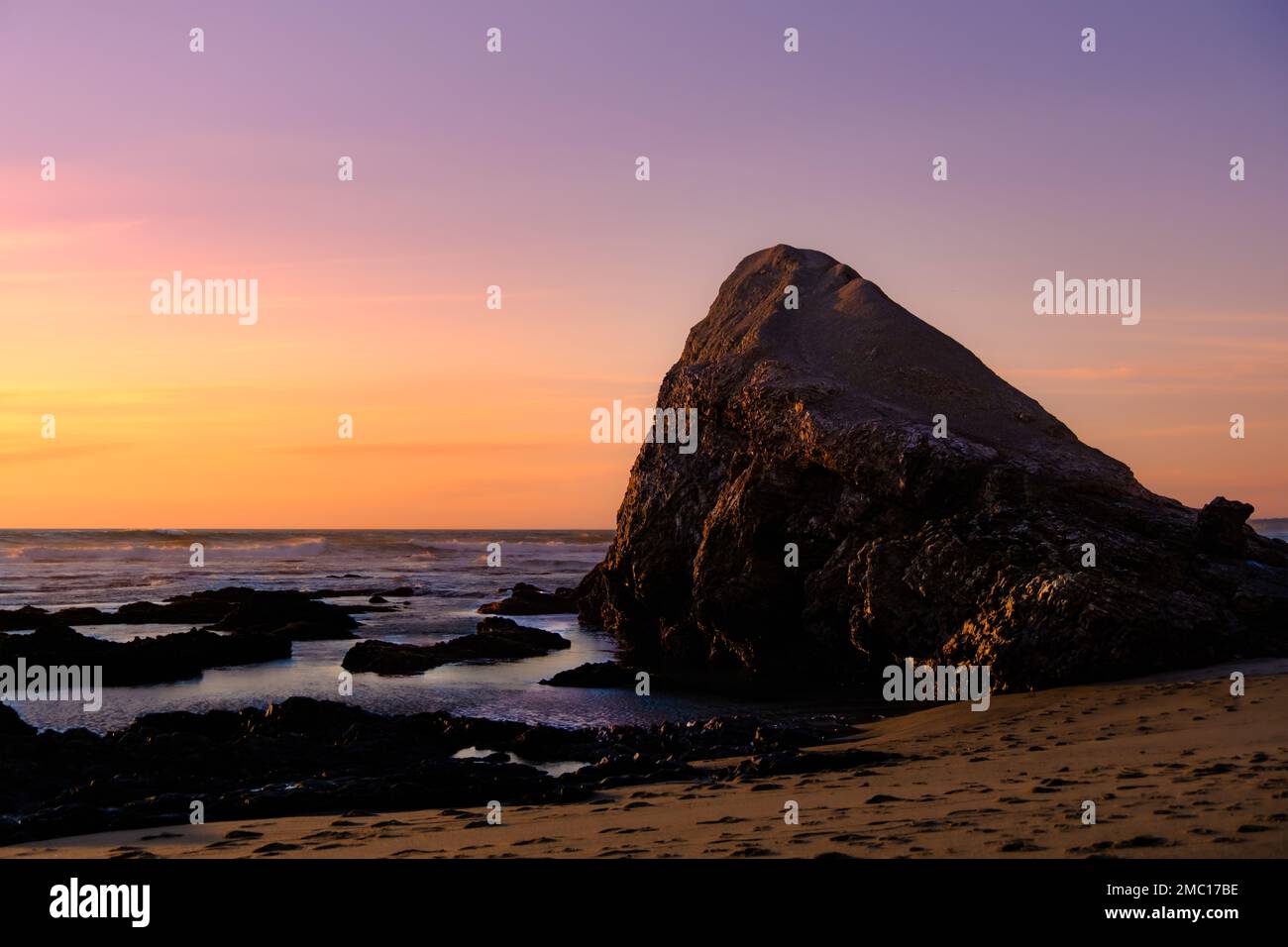 A beautiful rocky shore of the sea during purple sunset Stock Photo - Alamy