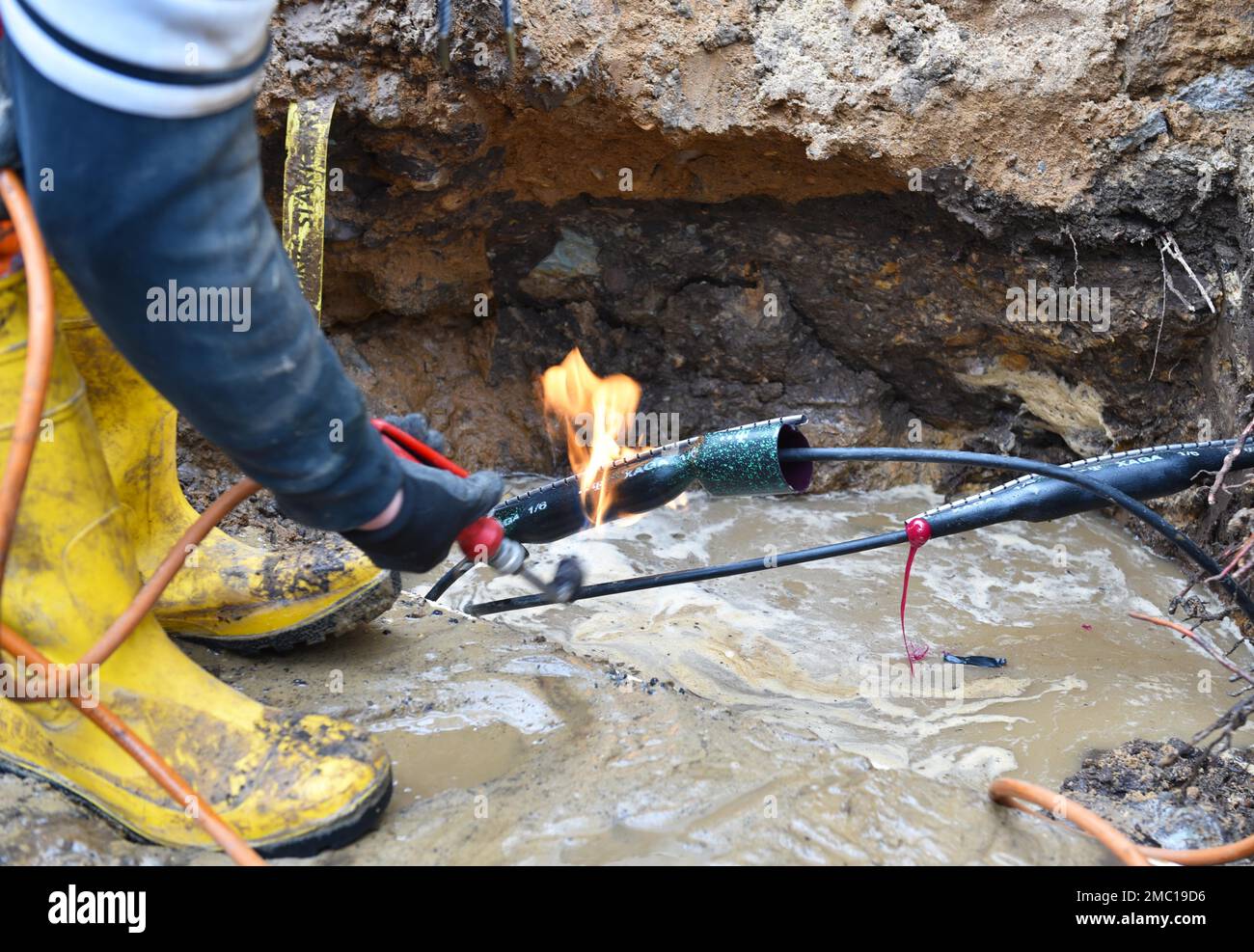 Worker repairs a telephone line, shrink sleeve is heated by Bunsen