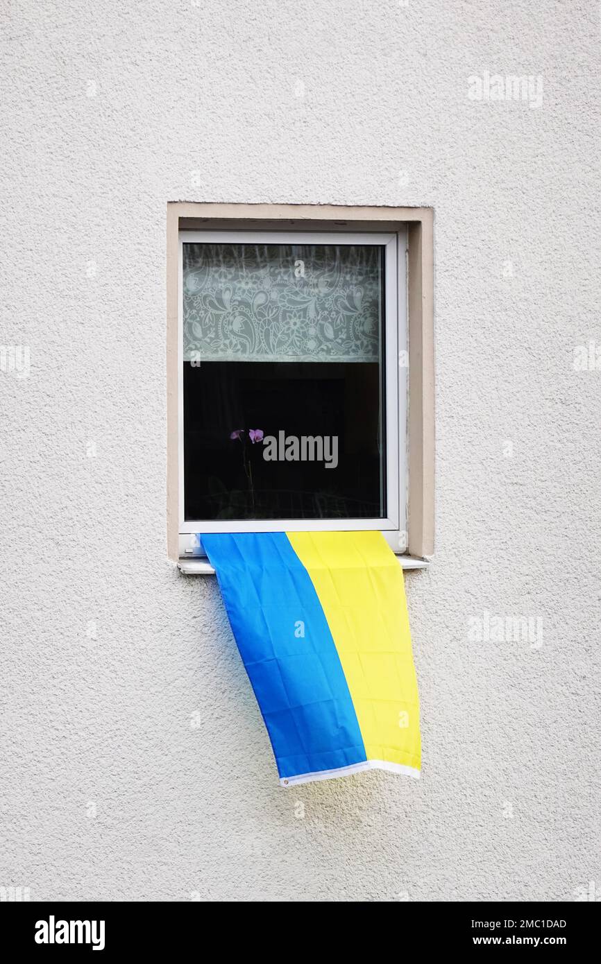 ukrainian flag hanging from window of residential building as a symbol of solidarity with ukraine Stock Photo