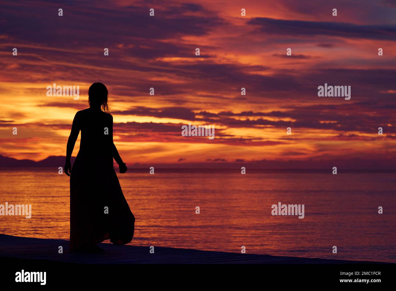 Silhouette of a woman watching the sunset over  Raja Ampat Islands, Indonesia. Stock Photo