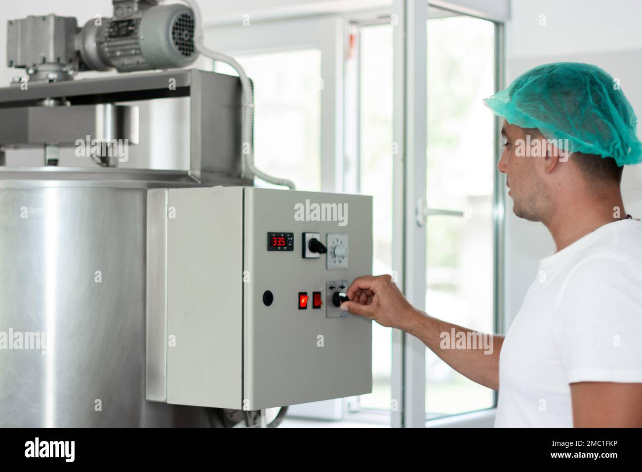 Cheese maker preparing the machine for the cheese making process Stock
