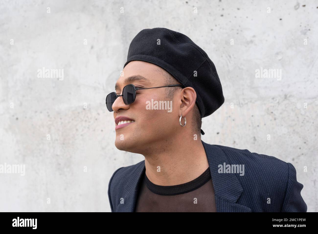 Young latin gay man with make-up on wearing a fashionable hat and sunglasses, isolated on a white background. LGBT Stock Photo