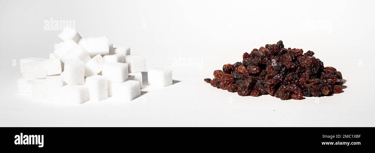 Healthy vs unhealthy sweets concept, refined sugar cubes and raisins