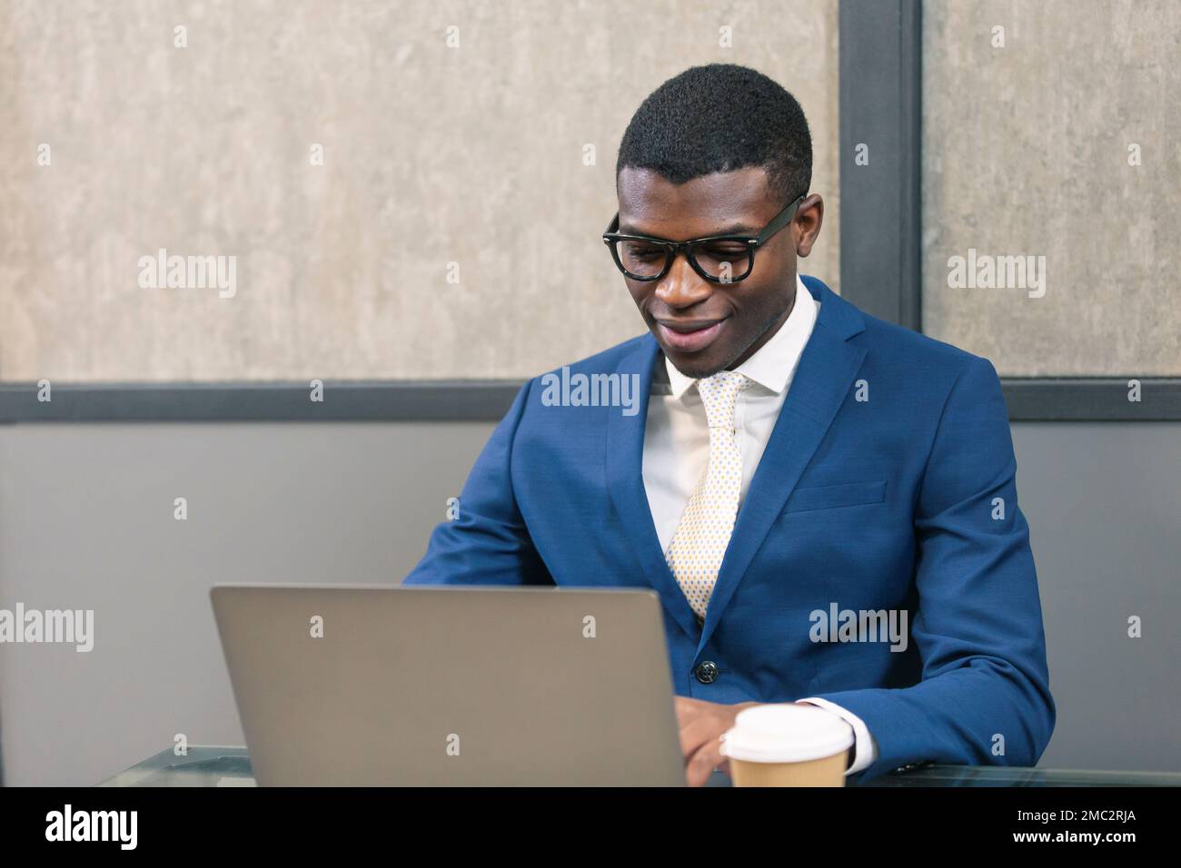 Smiling professional black business man using laptop computer working in office. Stock Photo