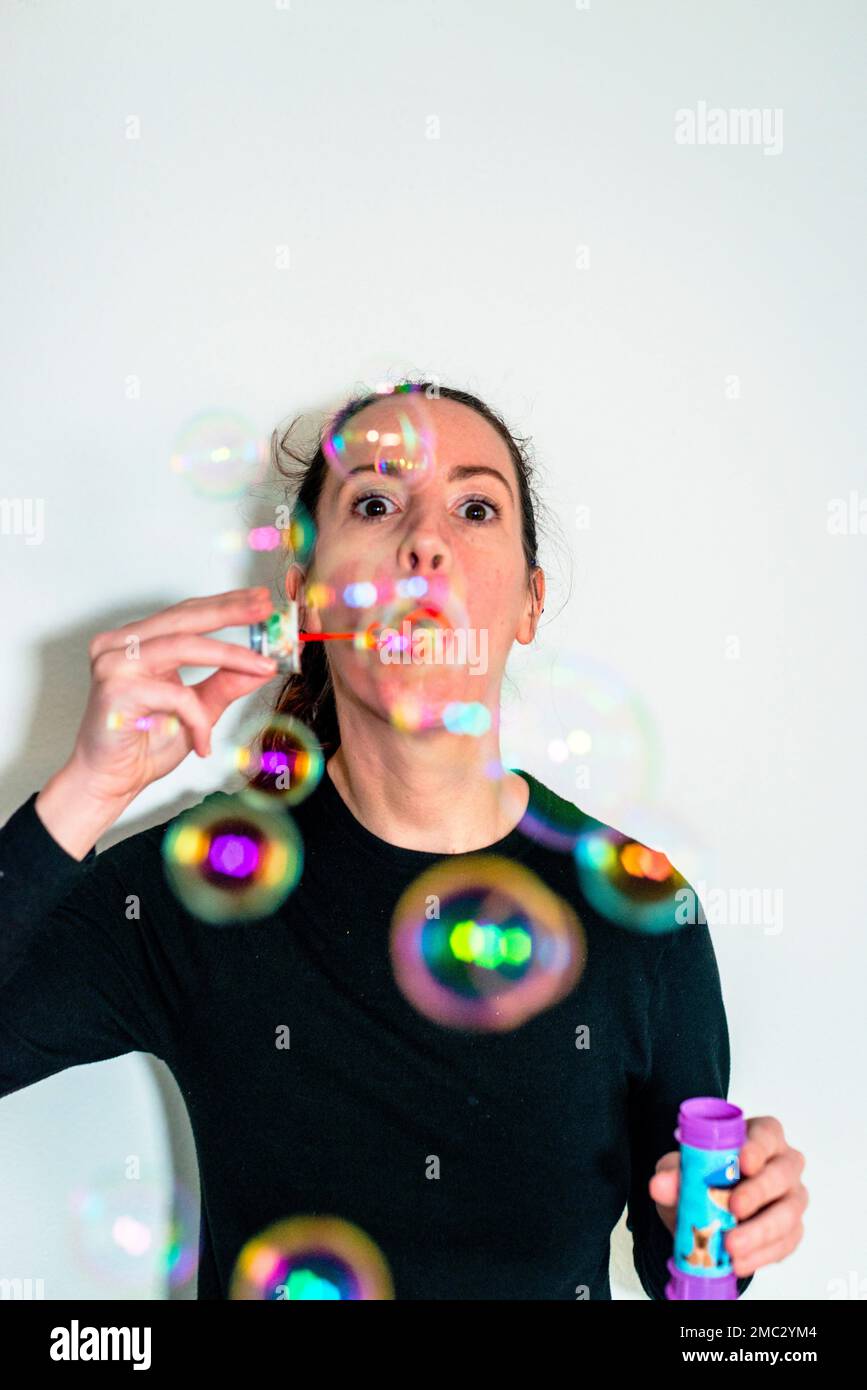 Young woman blowing soap bubbles indoor Stock Photo - Alamy