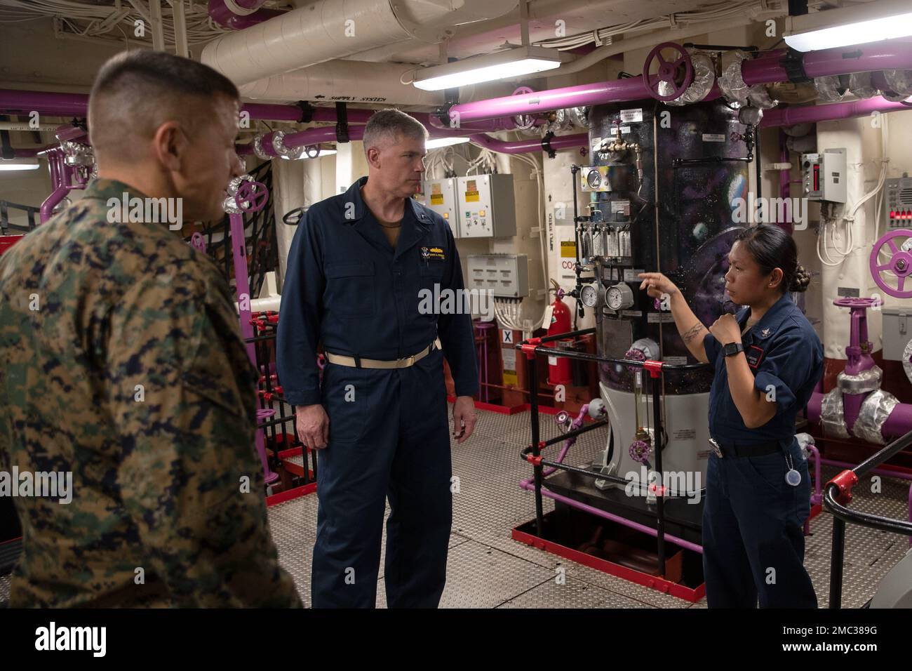 220624-N-XN177-2180 PACIFIC OCEAN (June 24, 2022) – U.S. Marine Corps Brigadier Gen. Fridrik Fridriksson, commanding general, 3rd Marine Expeditionary Brigade, left, and Rear Adm. Derek Trinque, commander, Expeditionary Strike Group 7, center, discuss fueling operations with Aviation Boatswain’s Mate (Fuels) 2nd Class Charlyn Andres in fuel room number one aboard amphibious assault carrier USS Tripoli (LHA 7), June 24, 2022. Tripoli is operating in the U.S. 7th Fleet area of operations to enhance interoperability with allies and partners and serve as a ready response force to defend peace and Stock Photo