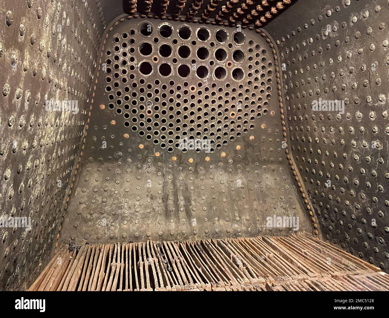 View into an old big firebox of a steam locomotive, inputs to the boiler pipes at the wall Stock Photo