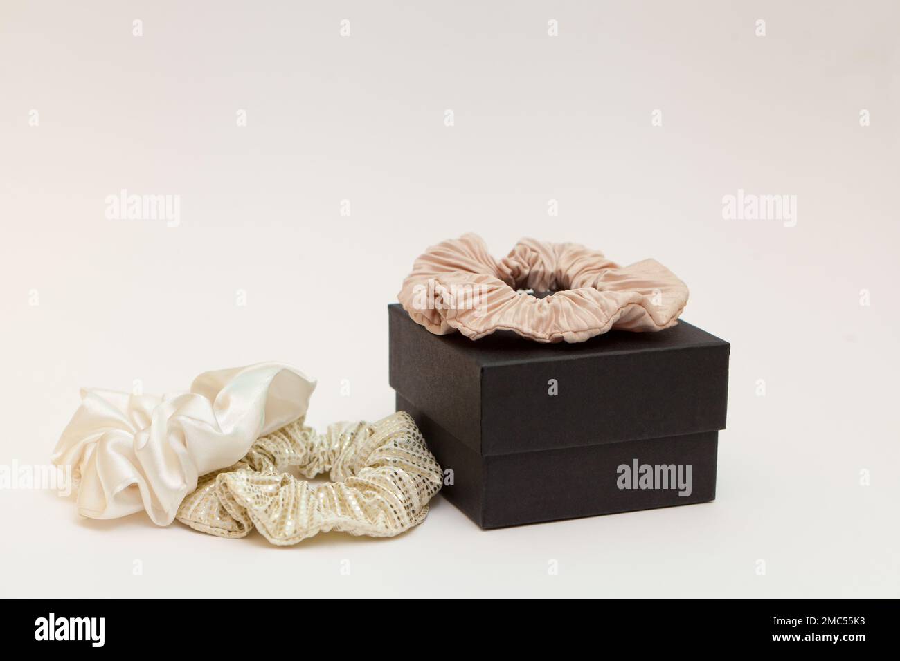gift box with beige silk scrunchies. lot or hair ties. Luxury tools for ladies. perfect for all hair Stock Photo