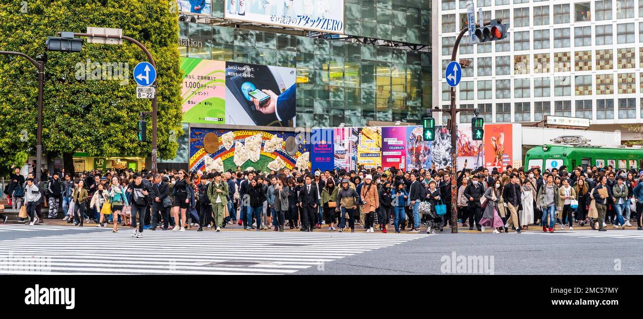 Tokyo. Shibuya. The famous scramble crossing. View across street of people outside JR Shibuya station waiting for lights to change to cross the road. Stock Photo