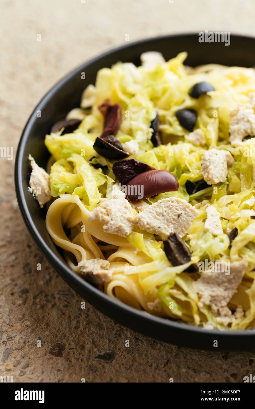 Savoy Cabbage on Tagliatelle with black olives and vegan feta. Stock Photo