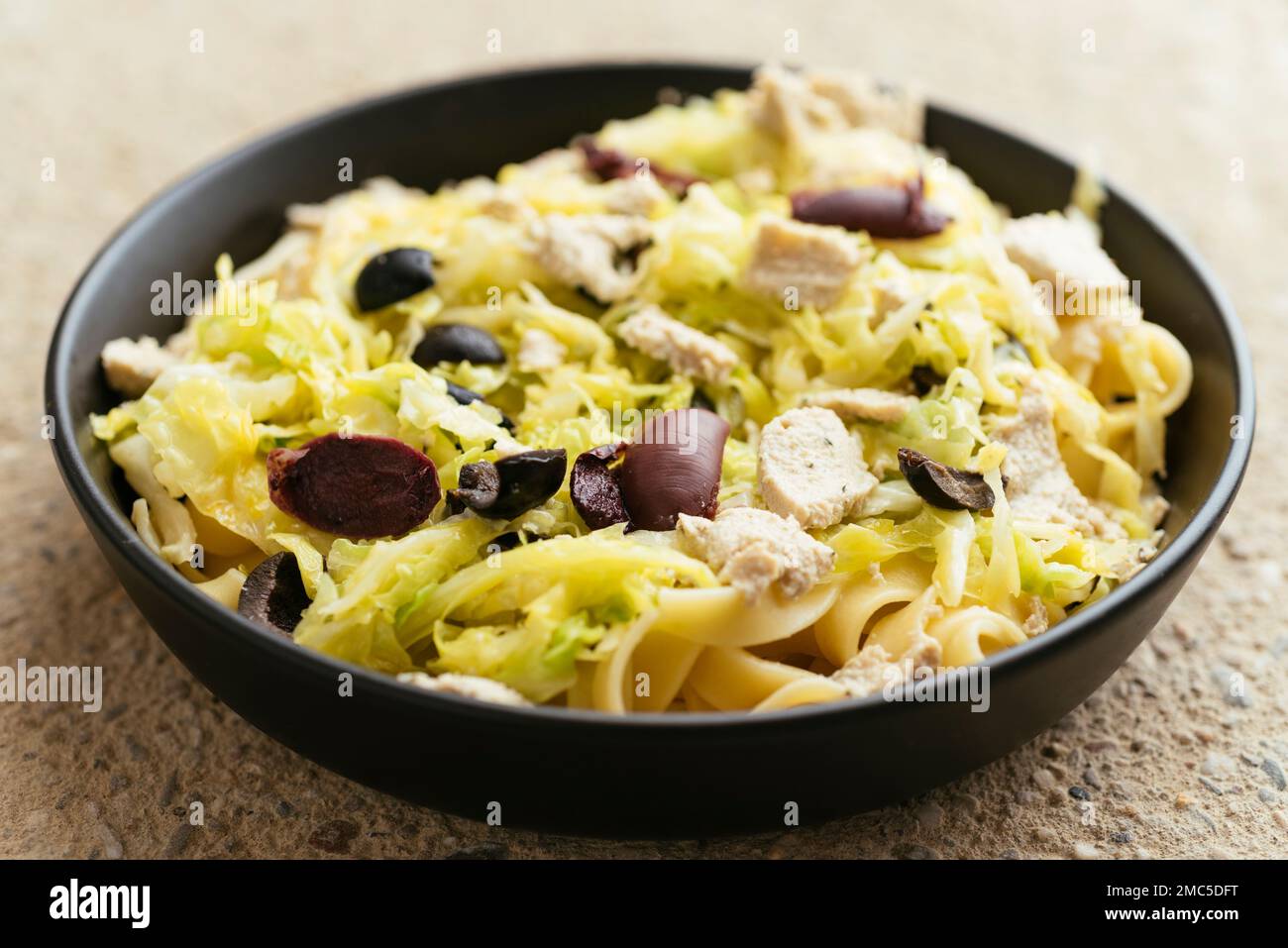 Savoy Cabbage on Tagliatelle with black olives and vegan feta. Stock Photo