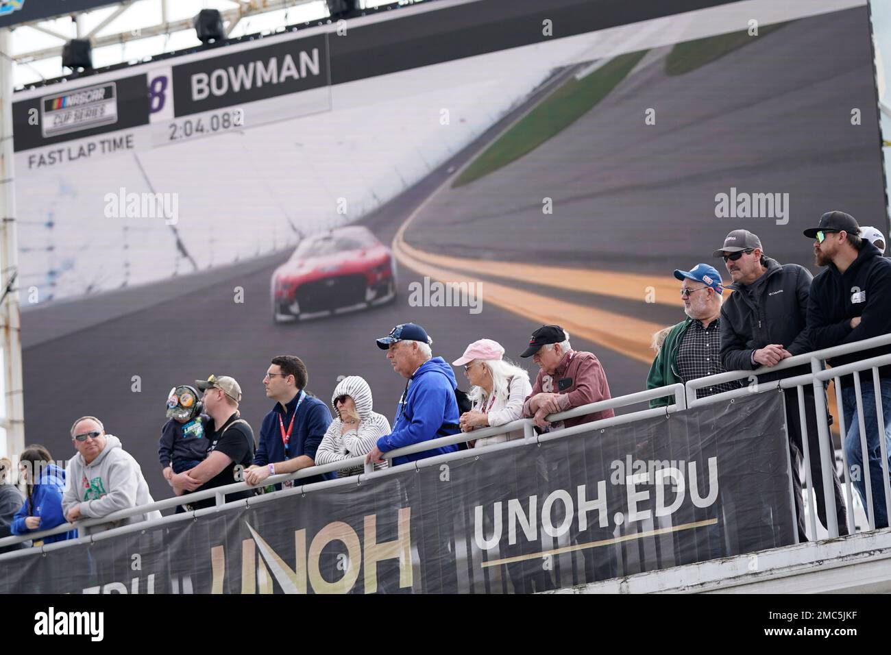 Fans watch a NASCAR auto race practice in front of a large screen monitor from the Fan Zone at Daytona International Speedway, Saturday, Feb