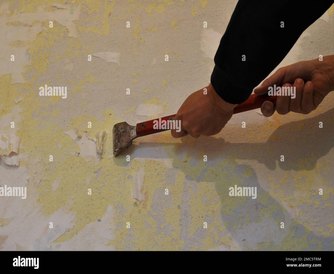 scraping off paper wallpaper and their remnants from the wall surface